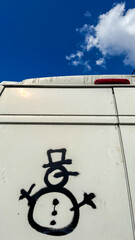 Graffiti snowman with inexplicable question mark, on van under azure sky, evokes quirky Festivus...