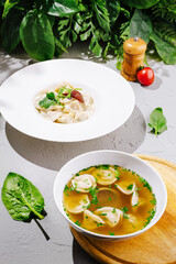 Fresh dumplings in broth with vibrant greens and herbs on display