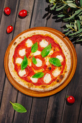 Freshly baked pizza with tomato and mozzarella on wooden platter
