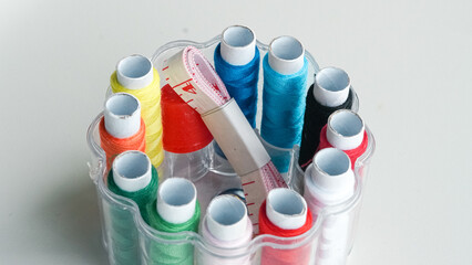 Colorful sewing threads, safety pins, and tape measure on white background