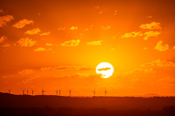 Sunset over wind turbines with horizon over land, Camperdown, Victoria, Australia
