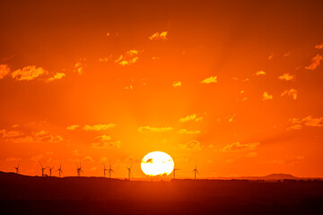 Sunset over wind turbines with horizon over land, Camperdown, Victoria, Australia