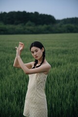 Young Asian woman in a field with a playful pose.