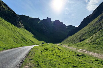 Curving road in Winnats Pass surrounded by grassy slopes, Peak District, England, UK.
