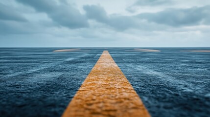 A low-angle view of an empty road stretching into the distance, marked by a solitary yellow line, under a cloudy sky, evoking feelings of solitude and reflection.