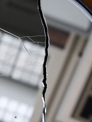 Cracked mirror showcases a single, dominant longitudinal crack that disrupts the otherwise flawless reflective surface.