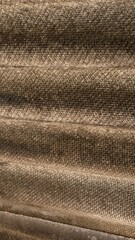 Textured corrugated surface casting subtle light and shadow patterns, likely part of a wall or...