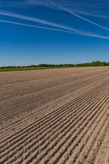 A rural landscape with a plowed empty field at the beginning of spring