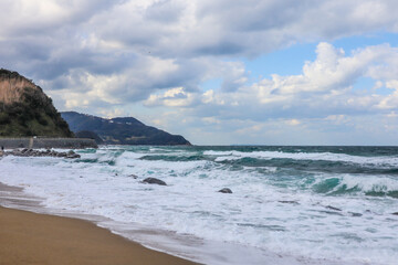 Dramatic Seascape with Crashing Waves and Cloudy Sky at Rocky Shore