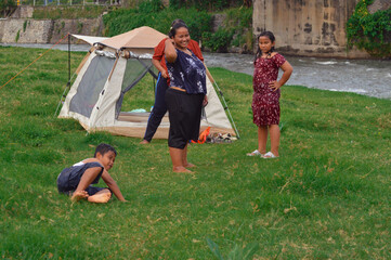 A playful moment captured as the young boy falls forward on the grass, and the nearby group...