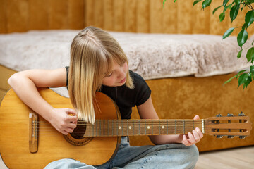 Young girl learning acoustic guitar at home