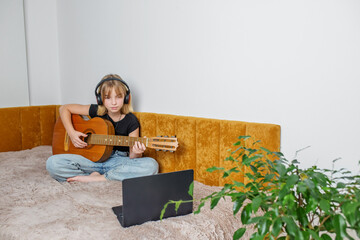 Preteen girl taking virtual guitar lesson from home