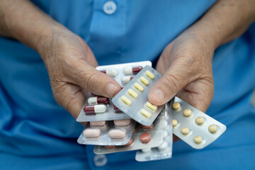 Asian elderly woman holding pill drug in hand, strong healthy medical concept.