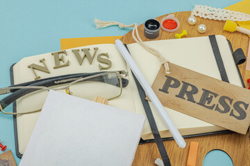 Flat lay of press badge, vintage camera, art supplies, notebook, and exhibition label