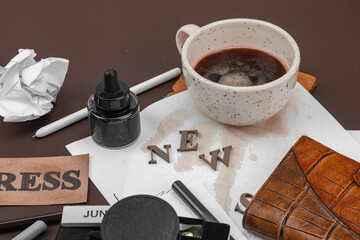 Creative flat lay with vintage camera, press tag, ink bottle, spilled coffee, and messy papers