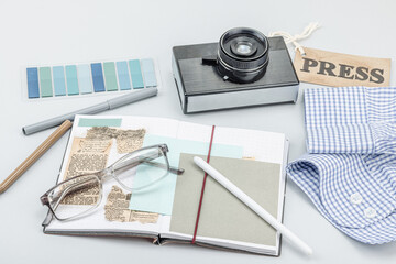 Flat lay of retro journalist essentials on blue background: camera, press badge, notebook