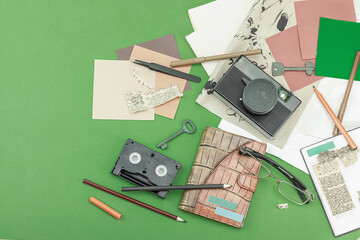 Flat lay with vintage camera, cassette, notebook, key and research tools on green background