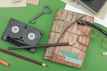Flat lay with vintage camera, cassette, notebook, key and research tools on green background