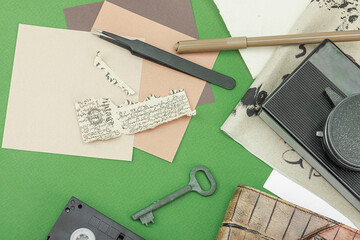 Flat lay with vintage camera, cassette, notebook, key and research tools on green background