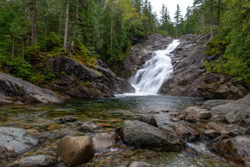 Obraz premium Waterfall cascading over rocky cliffs in lush greenery