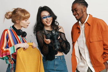 young adult colleagues socializing at workplace, woman holding camera, coworkers discussing...