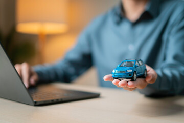 Signing auto insurance contract with car key and model car with a laptop in the foreground...