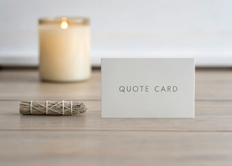Minimal setup with quote card, sage stick, and candle on wooden surface, creating calm and peaceful atmosphere for mindfulness or meditation practice