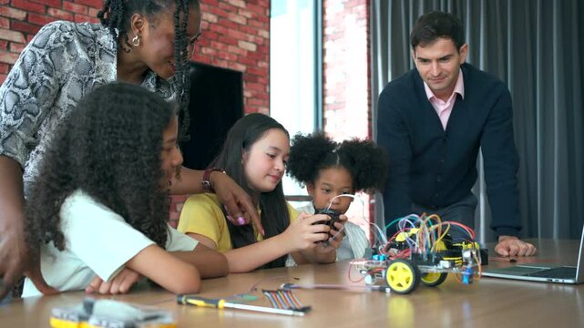 group of diverse high school students learns about programming and electronic robot components in a STEM class, with a teacher guiding them closely in an interactive learning environment.