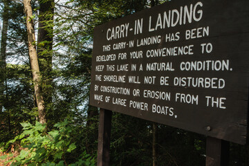 Sign explaining why Hemlock Lake in northern Wisconsin has a carry-in only boat launch, and the benefits to the lakeshore environment, near Woodruff, Wisconsin