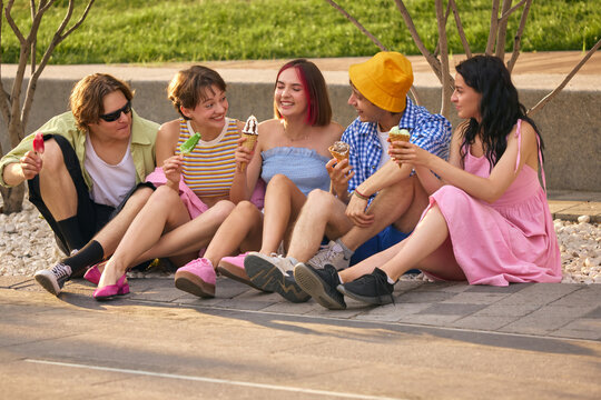 Friends enjoy ice cream together in a sunny outdoor park setting. Concept of leisure and bonding in public spaces. Urban tourism and culture