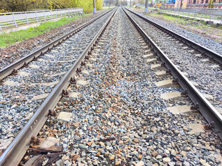 The railway tracks extend across a serene landscape, flanked by lush green trees and charming...