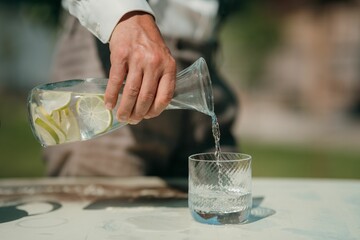 Pouring lemon-infused water outdoors on a sunny day.