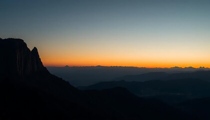 Serene mountain landscape at dawn with vibrant sky and layered silhouettes.