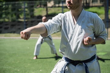Man practicing karate in traditional uniform outdoors.