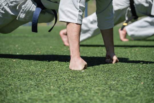 Close-up of karate students doing knuckle push-ups outdoors.