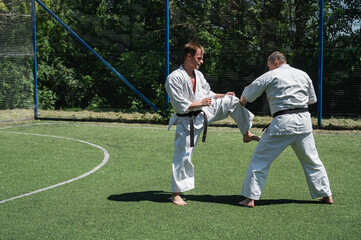 Man in white karate gi delivering a front kick to his sparring partner.