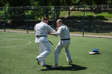Obraz premium Karate fighters practicing blocking and striking techniques outside.
