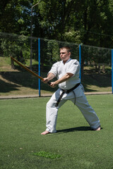Obraz premium Martial artist training with wooden sword on sports field.