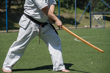 Obraz premium Close-up of martial artist holding wooden sword in stance.