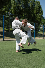 Martial arts sparring with knee strike outdoors.