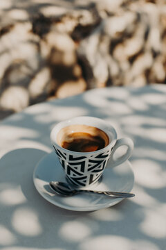 Ceramic cup of tasty black coffee a on a table in a street cafe in a sunny morning. Selective focus.