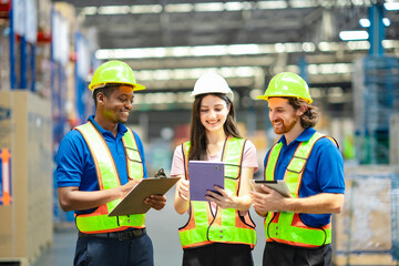 Male and female workers in hard hats pointing at tablet, reviewing stock information. Efficient warehouse teamwork and supply chain management in logistics environment.