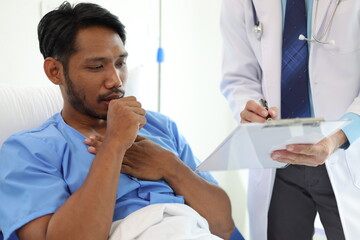 Obraz premium Doctor interviews a sick patient in a hospital room. Doctor in a hospital examination room is diagnosing a sick man with cough and chest tightness and sore throat.