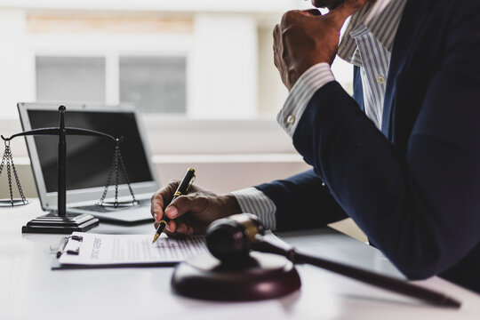 Lawyer reading legal documents and preparing to sign a contract. Lawyer is carefully reviewing legal documents at his desk.