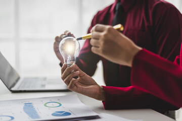 Two business professionals working together, analyzing financial documents and holding a bright...