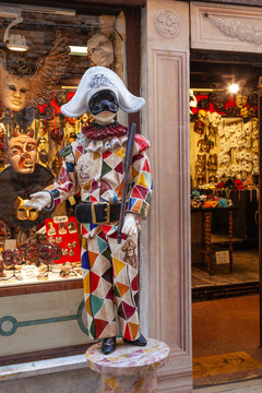 Signage using Harlequin statuette outside the popular Ca Macana Carnival mask shop, 19 April 2018, Dorsoduro, Venice, Italy, symbolising a playful Devil from Passion Plays