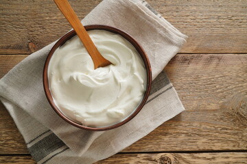 Sour cream in bowl on wooden table. Natural yogurt. Top view.