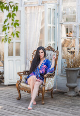 Brunette woman in blue kimono dress at terrace, Boho style, modern trends