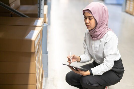Muslim female wearing hijab warehouse worker holding tablet checks stock on shelf storehouse. businesswoman islamic entrepreneurs rent a warehouse.