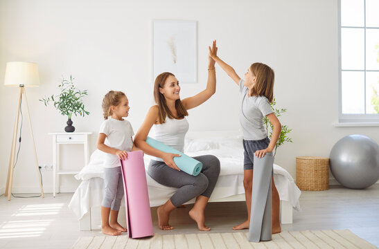 Mother gives kids a high five during a home sports workout. The family stays active together, enjoying fitness training in home gym, creating a positive and energetic atmosphere during session.